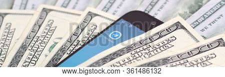 Smartphone Screen With Telegram App And Lot Of Hundred Dollar Bills. Business And Social Networking 
