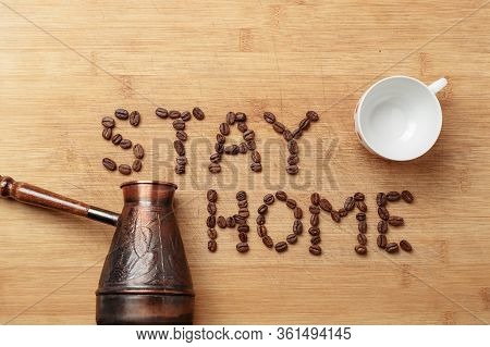 The Slogan Stay Home As Inscription Lined With Roasted Coffee Beans On A Homemade Wooden Cutting Boa