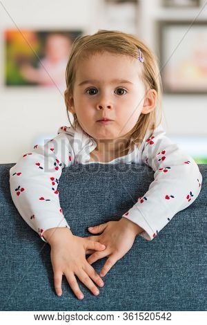 Two Year Old Girl With Big Eyas Portrait Looking At Camera, Indoor Shoot With Natural Light. Develop