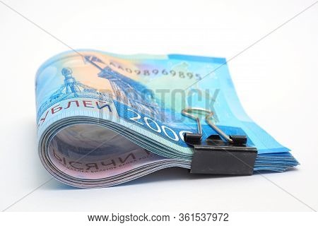 A Rolled Up Bundle Of Russian Banknotes Of Two Thousand Rubles Lies On A White Paper Background. Ban