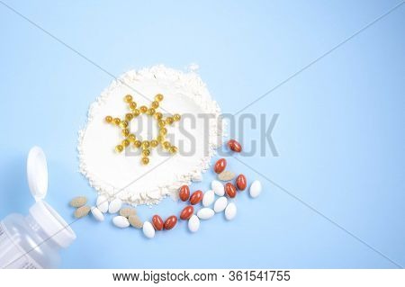 Vitamin D Yellow Pills In The Shape Of Sun On White Lecitin Powder In Sky Blue Background, Nutrition