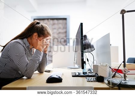 Overworked And Frustrated Young Woman In Front Of Computer In Office