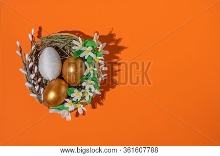 Easter Eggs In Basket Filled With Straw And Yellow Flowers And Willow. Preparation For Holiday. East