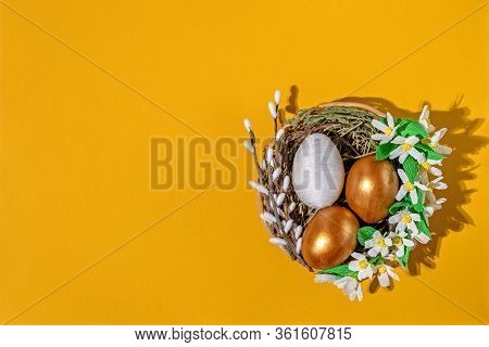 Easter Eggs In Basket Filled With Straw And Yellow Flowers And Willow. Preparation For Holiday. East