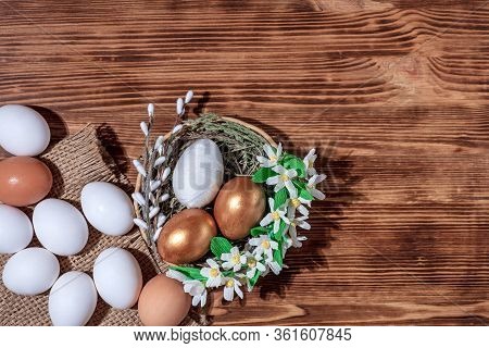 Easter Eggs In Basket Filled With Straw And Yellow Flowers And Willow On Wooden Rustic Vintage Backg