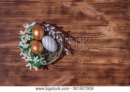 Easter Eggs In Basket Filled With Straw And Yellow Flowers And Willow On Wooden Rustic Vintage Backg