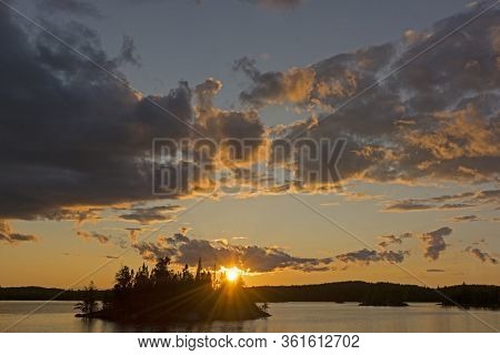 Sun Peeking Through The Clouds At Sunset On Saganagons Lake In Questico Provincial Park In Ontario