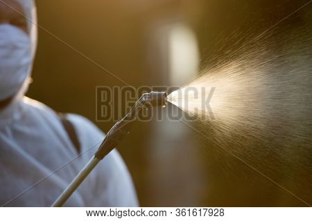Man in protective equipment decontaminating and spraying on a public place as a prevention against Coronavirus disease 2019, COVID-19. Coronavirus pandemic.