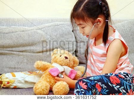 A Young Asian Girl Playing Doctor With Her Brown Teddy Bear