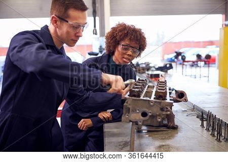 Male And Female Students Work On Car Engine Block On Auto Mechanic Apprenticeship Course At College