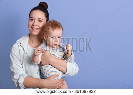 Horizontal Shot Of Happy Smiling Mum Holding Her Little Son In Hands, Infant Wearing Striped Bodysui