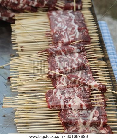 Skewers Of Raw Lamb And Mutton Called Arrosticini In Italian Language At The Restaurant Before Cooki