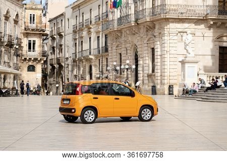 Siracusa, Sicily - February 13, 2020: Bright Orange Fiat Panda Car Driving On A Piazza Duomo Town Sq
