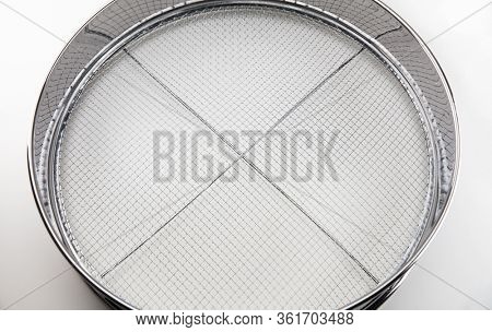 Screening. A chrome sieve or screen used for filtering wanted or unwanted elements.
Also called mesh strainer or sift. Focus at center of screen net.