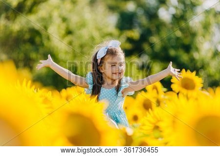 Little Cheerful Girl In A Field Of Yellow Sunflowers. Child And Sunflower, Summer, Nature And Fun. S