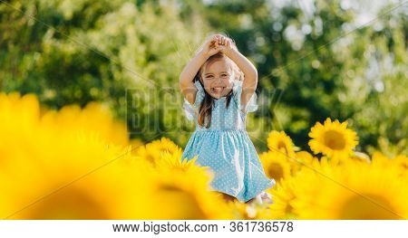 Little Cheerful Girl In A Field Of Yellow Sunflowers. Child And Sunflower, Summer, Nature And Fun. S