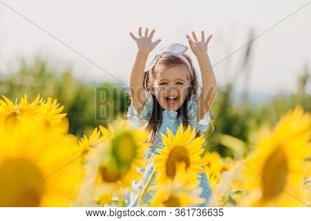 Little Cheerful Girl In A Field Of Yellow Sunflowers. Child And Sunflower, Summer, Nature And Fun. S
