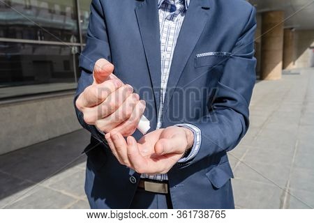 Businessman In A Blue Suit Using Small Portable Antibacterial Sanitizer Applying Antiseptic For Wash