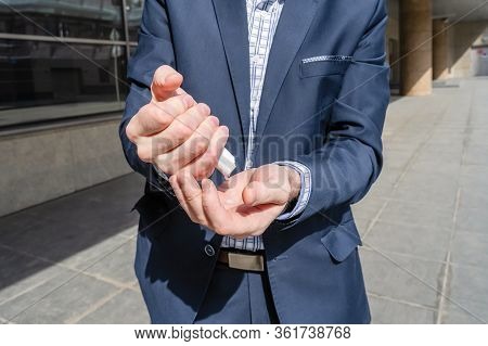 Businessman In A Blue Suit Using Small Portable Antibacterial Sanitizer Applying Antiseptic For Wash
