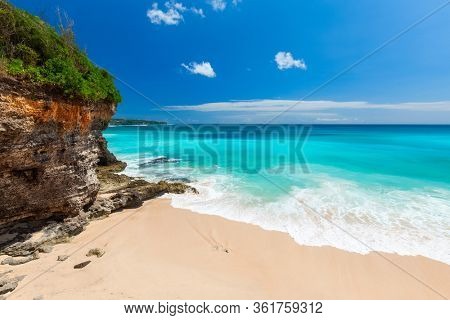 Balinese sandy beach with green steep cliff and torquoise water. Bali, Indonesia