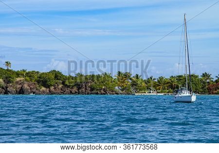 A Small White Sail Boat Anchored Near The Coast Of A Puerto Rican Island.