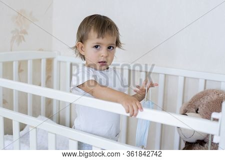 Concept Coronavius Covid-19 Quarantine, Security, Hygiene. Little Cute Baby Is In The Crib At Home A