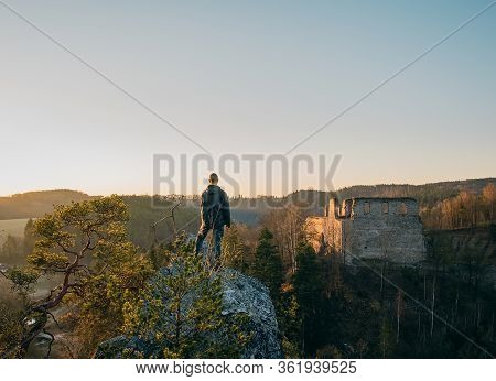 Young Man In Jacket, Pants Standing And Looking To Ruin Divci Kamen From Rock. Czech Republic