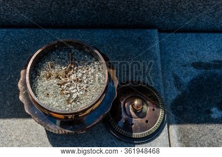 Top View Of Opened Bronze Incense Bowl Filled With Small Round Glass Beads On Concrete Slab.