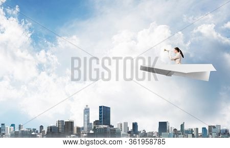 Business Woman Playing Trumpet Brass In Blue Sky. Young Lady In White Business Suit And Gloves Flyin