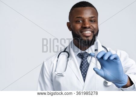 Vacination During Quarantine. Smiling African Male Doctor Holding An Injection Over White Background