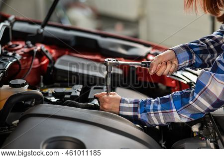 Female Auto Mechanic Unscrewing A Nut To Replace A Car Spark Plug.
