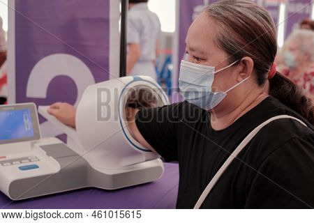 Fat Asia Senior Woman Inserted Her Hand Into The Blood Pressure Monitor. Healthcare And Madical Chec