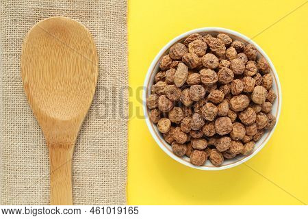 Chufa, Tigernut, Earth Almond On White Ceramic Bowl And Eco Canvas Bag Near Wooden Spoon On Yellow B