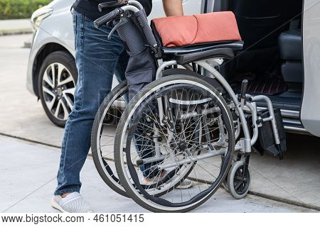Asian Woman Folding And Lift Up Wheelchair Into Her Car. Accessibility Concept.