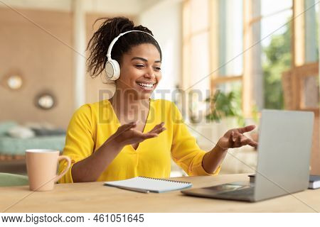 Happy Black Lady In Wireless Headphones Video Calling Via Laptop, Communicating With Remote Friend O
