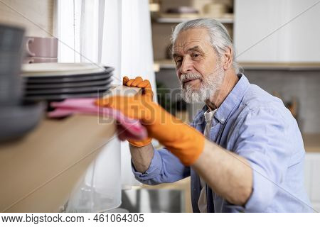 Ocd Concept. Senior Man Cleaning Dust From Shelf In Kitchen