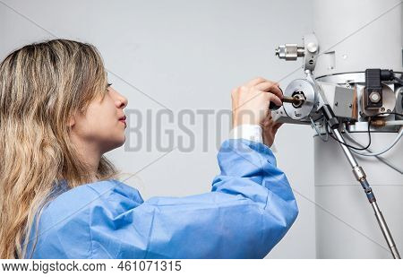 Young Female Scientist Loading A Specimen Using A Sample Holder Into A Transmission Electron Microsc