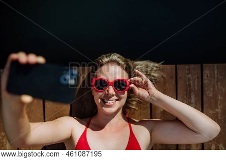 Rlaxed Woman Taking Selfie When Lying On A Pier By Natural Lake In Summer
