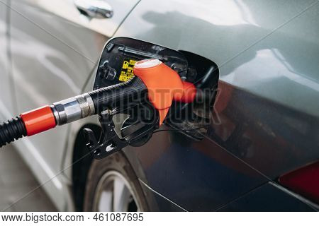 Fuel Nozzle Filling Petrol Into Car Tank At Gas Station. Image With Selective Focus