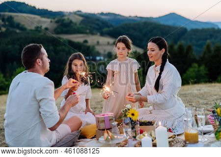 Happy Family With Children Having Picnic In Park, Clebrating With Sparklers.