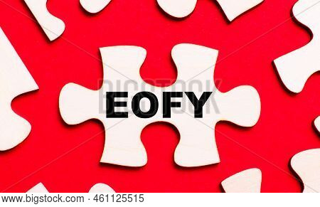 On A Bright Red Background, White Puzzles. In One Of The Pieces Of The Puzzle, The Text Eofy