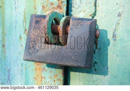 A Padlock Hangs On Old Metal Garage Or Warehouse Doors.