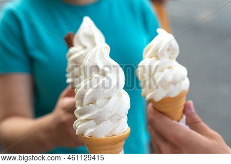 Several Soft Vanilla Ice Creams With Chocolate Sticks In Hands