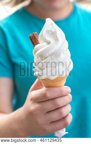 Soft Whipped Vanilla Ice Cream With Chocolate Stick In Waffle Cone In Hands