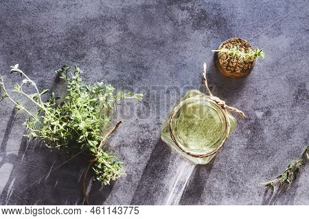 Thyme Essential Oil In Open Bottle, Cork And Fresh Thymus Plants On Gray Marble Table, Flat Lay