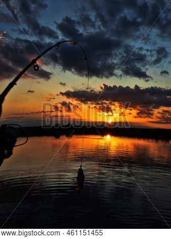 Fishing At Sunset. Catching Predatory Fish On Spinning. Sunset Colors On The Water Surface, Sunny Pa