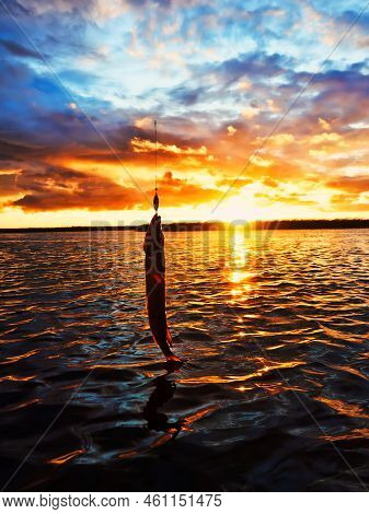 Fishing At Sunset. Catching Predatory Fish On Spinning. Sunset Colors On The Water Surface, Sunny Pa