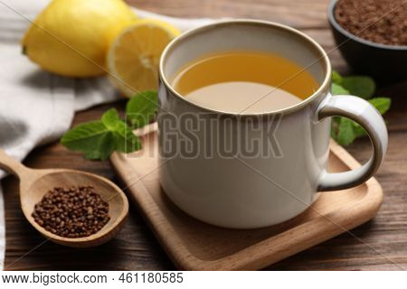 Cup Of Aromatic Buckwheat Tea And Spoon With Granules On Wooden Table, Closeup