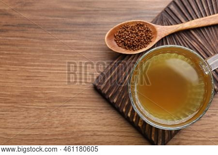 Cup Of Aromatic Buckwheat Tea And Granules On Wooden Table, Top View. Space For Text