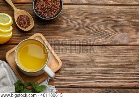 Cup Of Aromatic Buckwheat Tea, Granules And Lemon On Wooden Table, Flat Lay. Space For Text